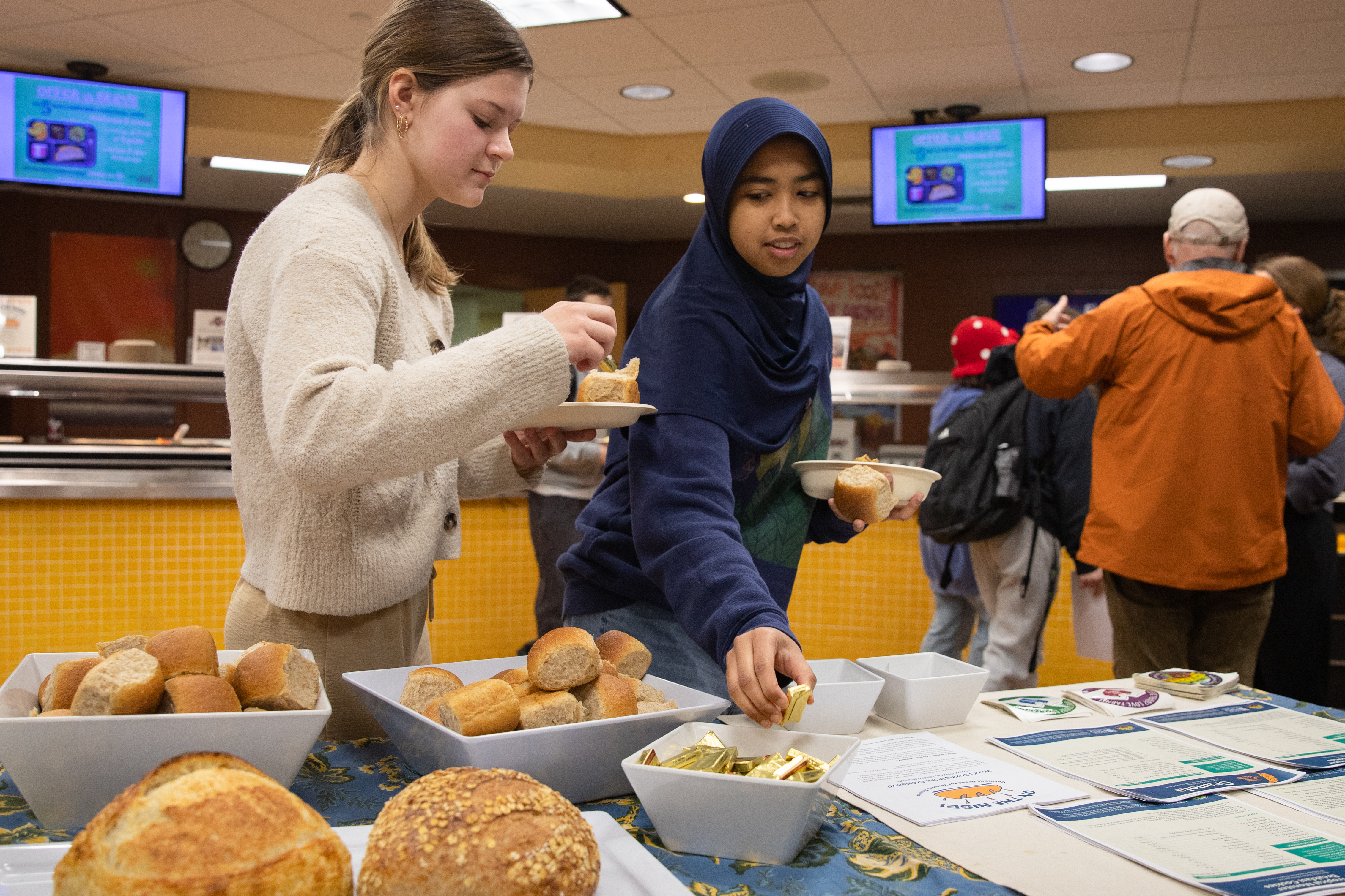 Two students are seen sampling the new local rolls in the cafeteria in Brattleboro