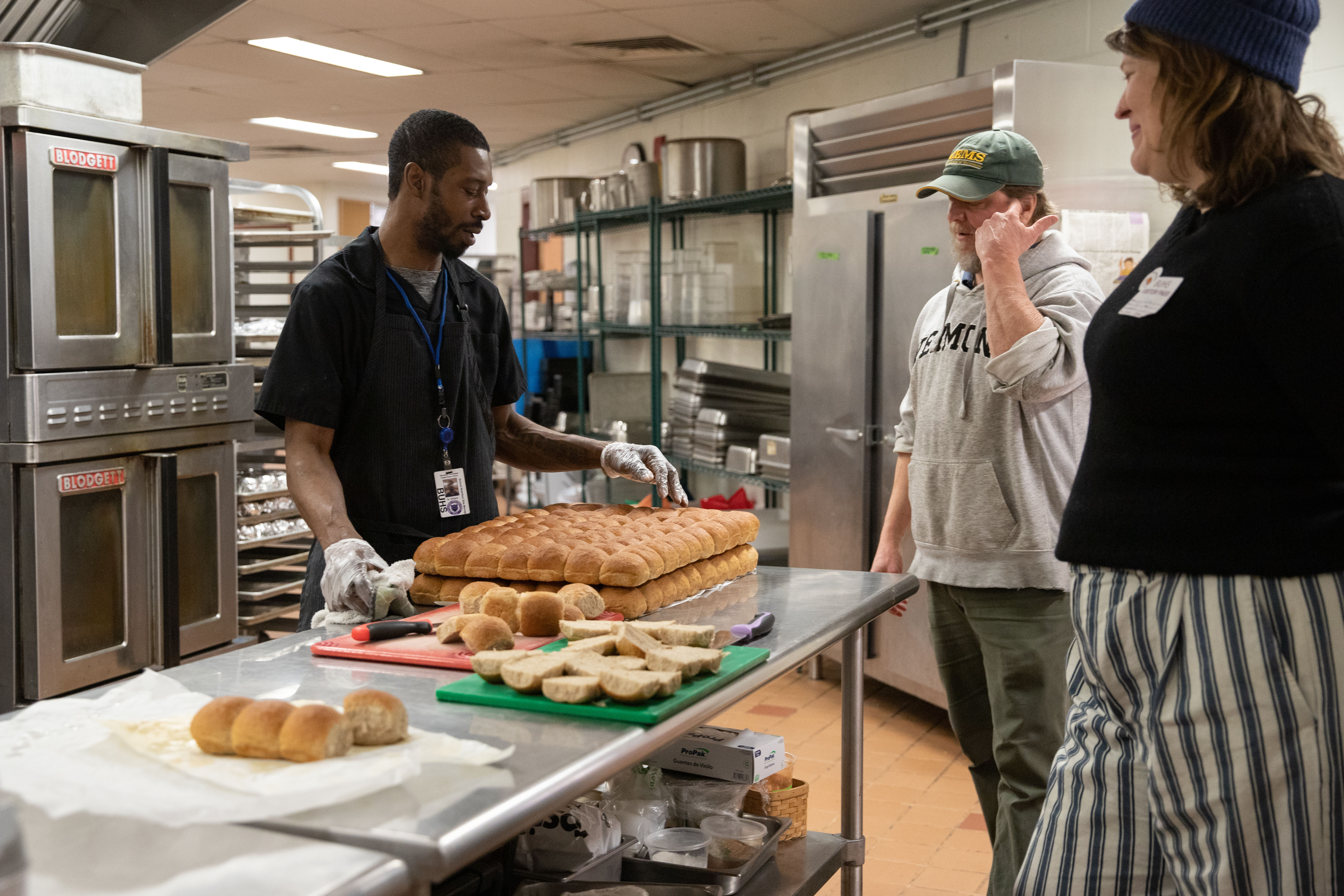 A Vermont school nutrition professional prepares several trays of local rolls in the school cafeteria while talking with partners in the project, including NOFA-VT's Farm to School Local Procurement Specialist Becca Perrin