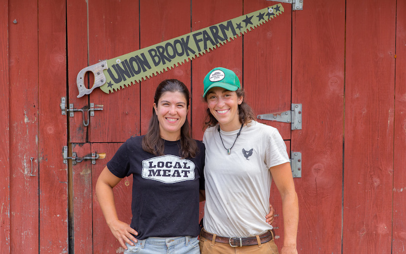 Union Brook farmers in front of a red barn wall