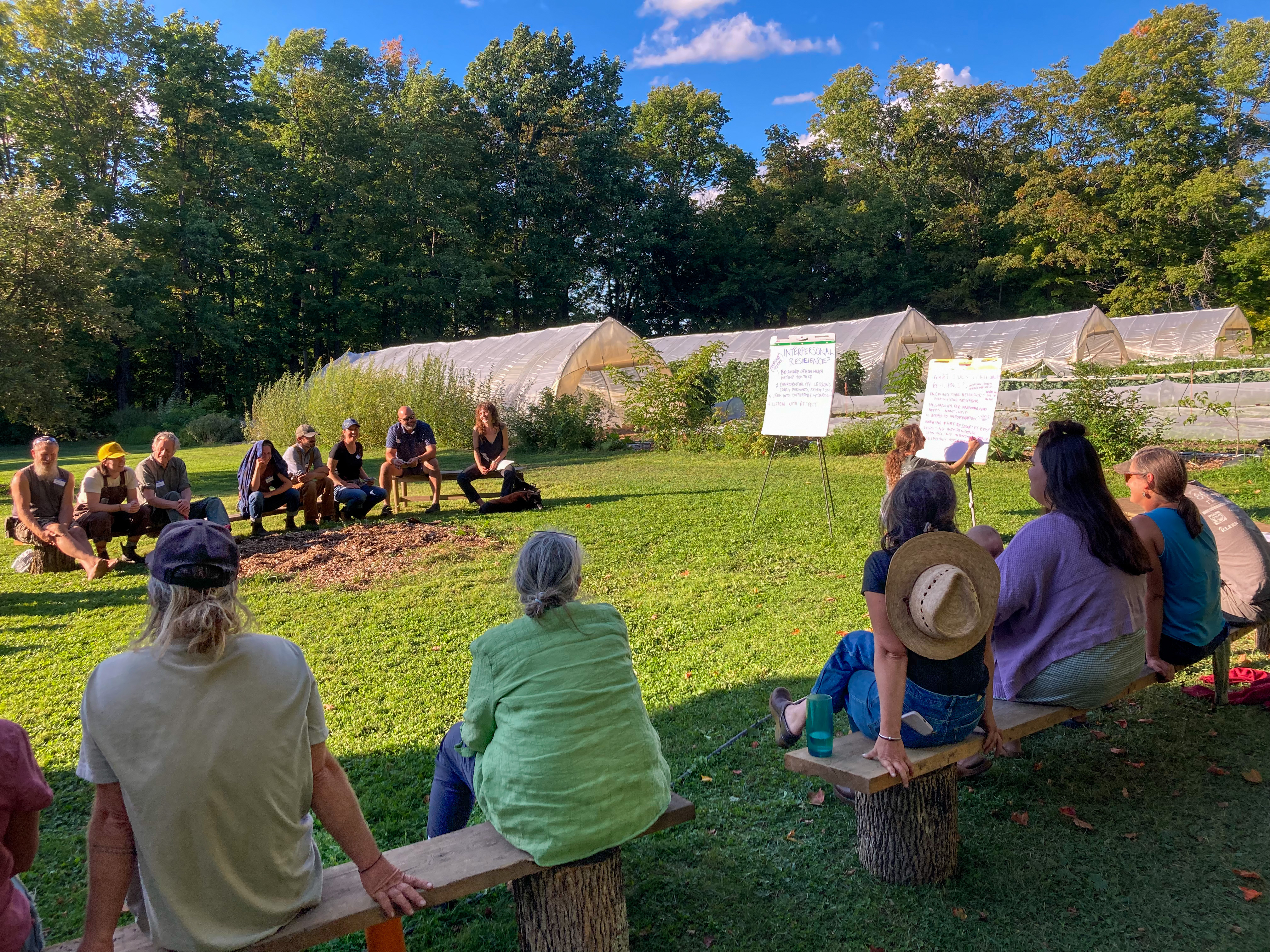 farmers and other food system stakeholders gathered at Breadseed Farm in Vermont's Northeast Kingdom, seated in a big circle with farm fields in the background, and adding notes to a large flipchart