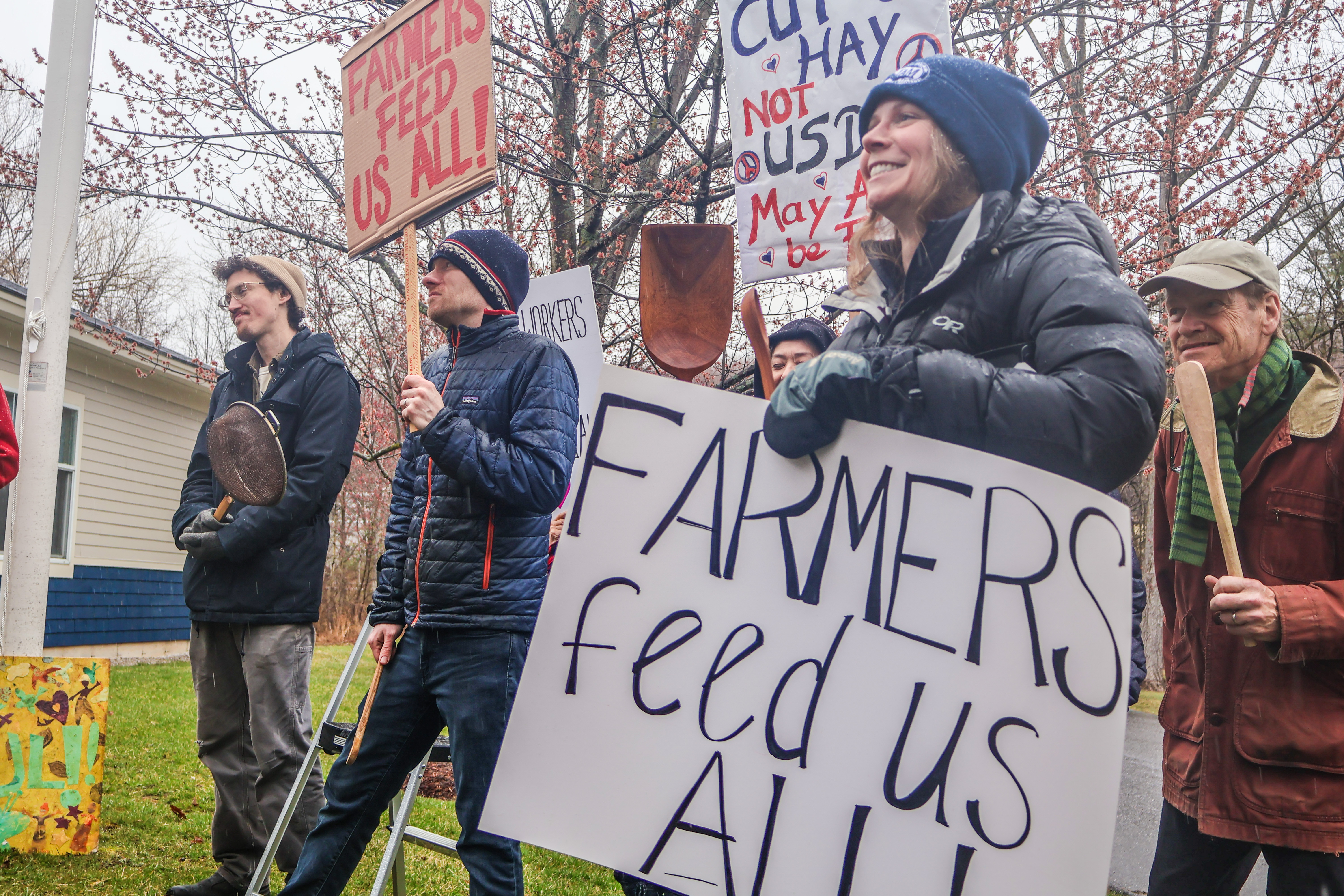 Farmers, farmworkers, and NOFA-VT members at the Farmer Day of Action at the Middlebury USDA offices holding signs reading "Farmers Feed Us All" and "Cut Hay, Not USDA"