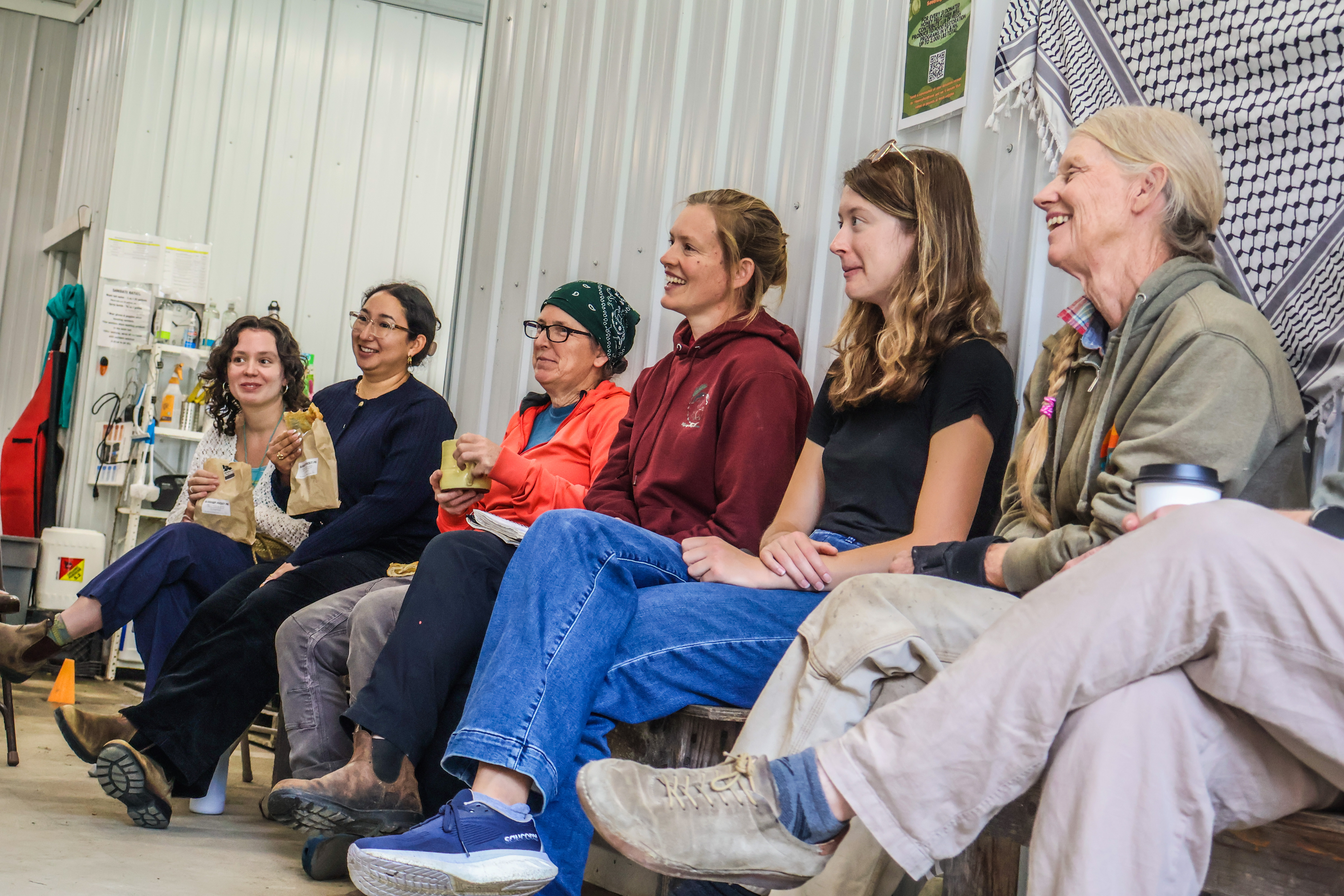 Vermont farmers Amy Huyffer, Shona Samford-Long, and Suzanne Long are seated in a barn flanked by members of Senator Welch's staff for a farmer roundtable hosted at Honey Field Farm