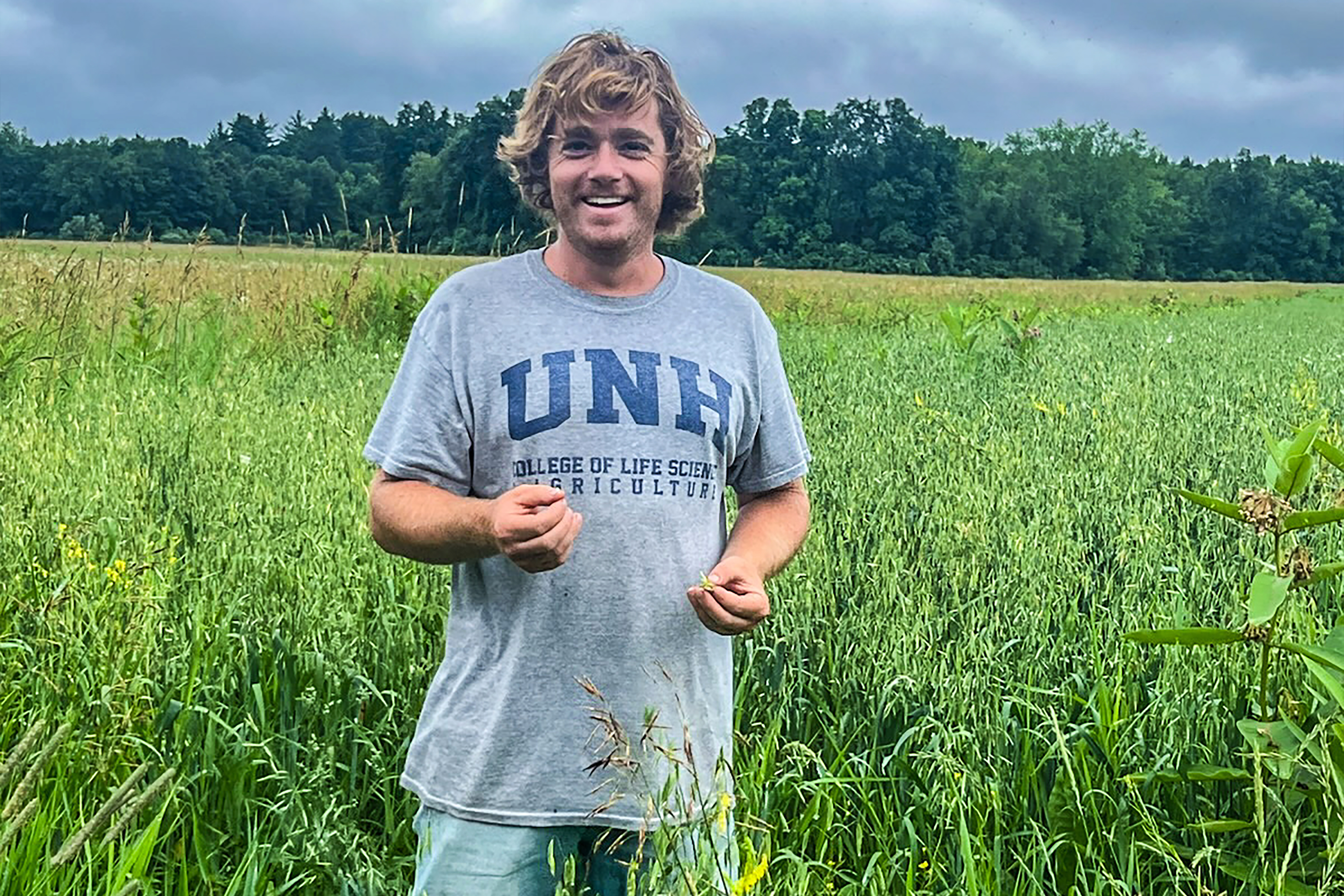 Tyler of Granite Grains stands smiling in a field full of organic grain