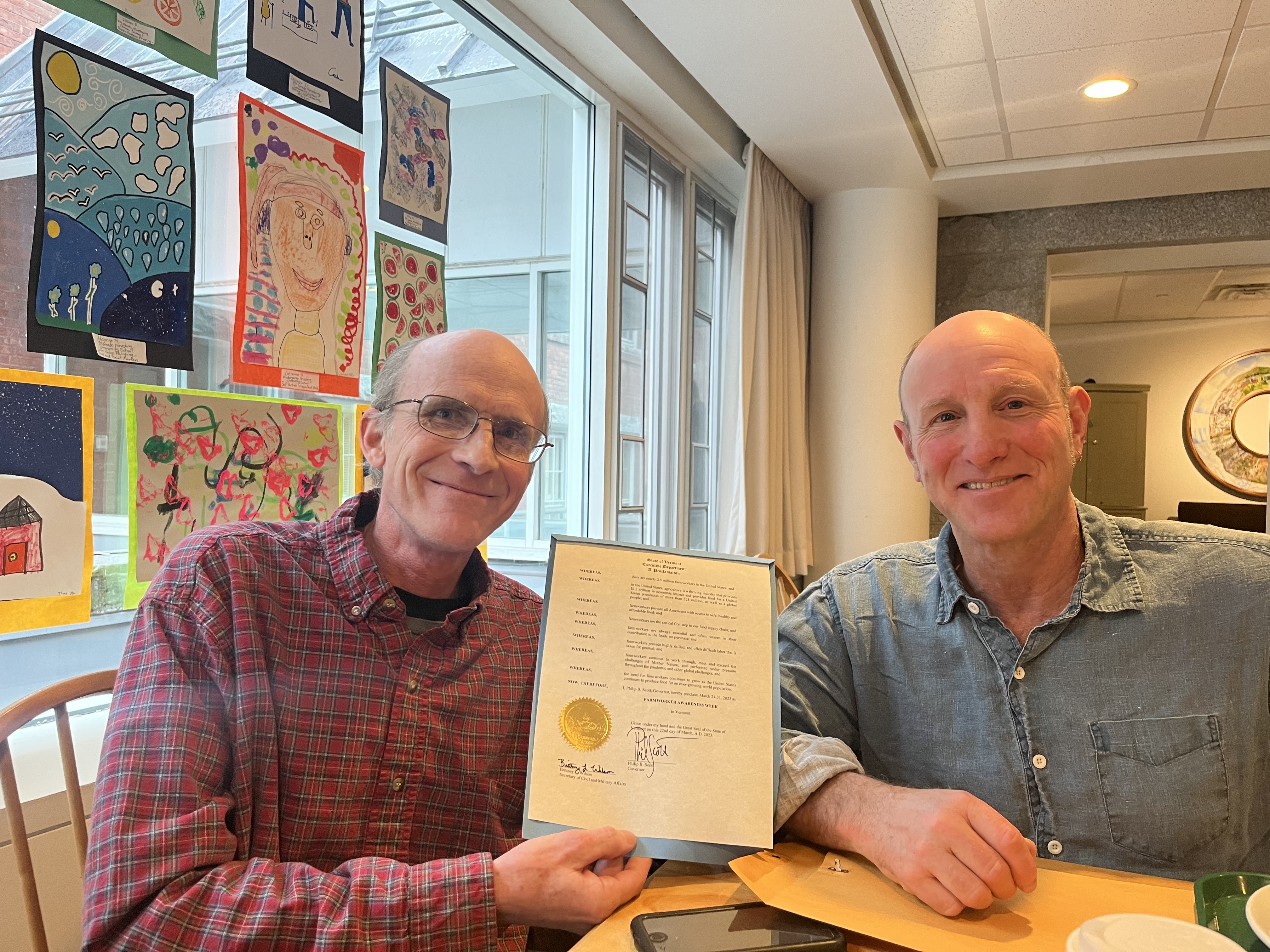 Buster Caswell and Dan Baker, in the state house cafeteria, holding a copy of Governor Scott's Farm Worker Awareness Week proclamation