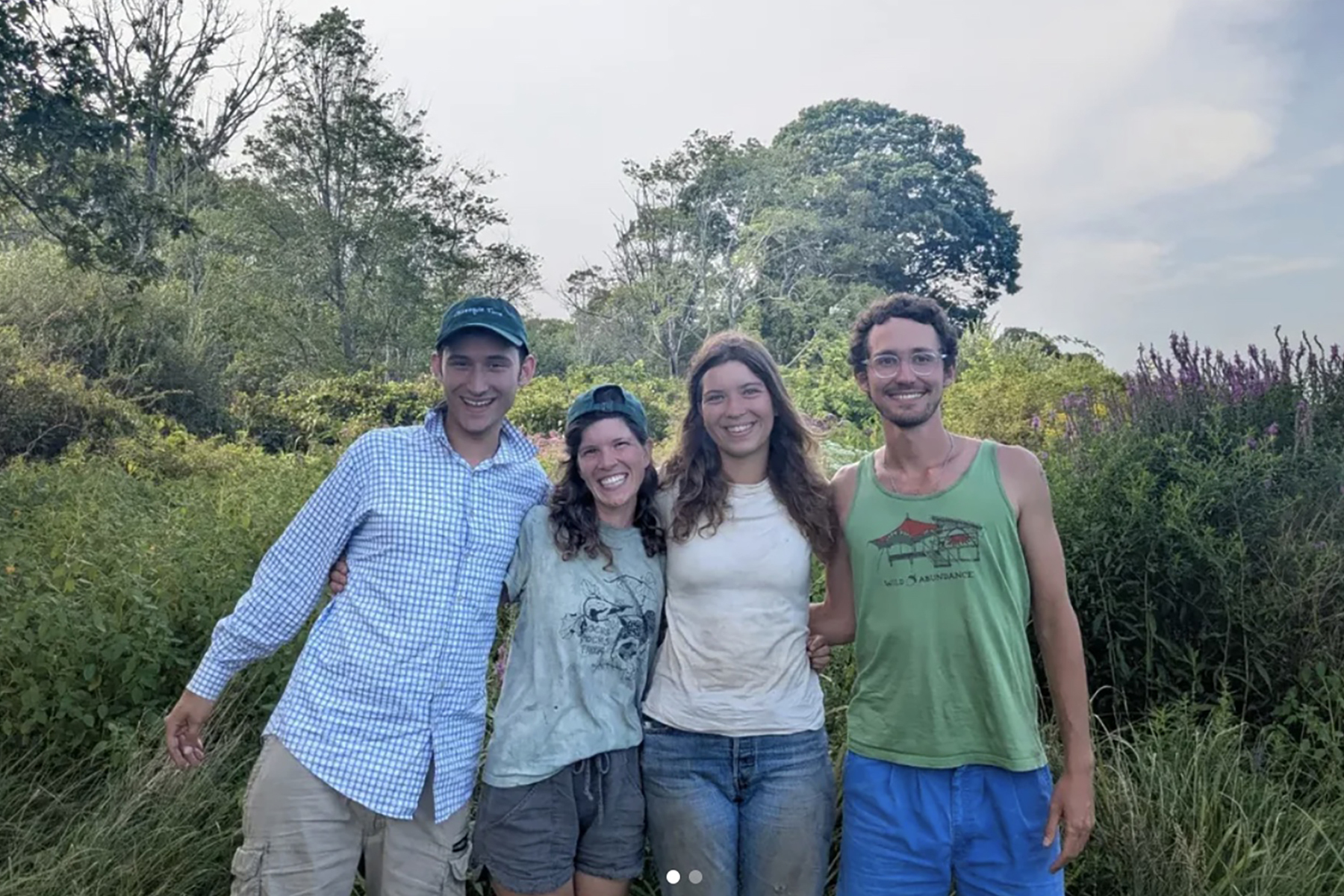 Farmers from Osamequin Farm are pictured smiling arm in arm in front of a field of perennial flowers