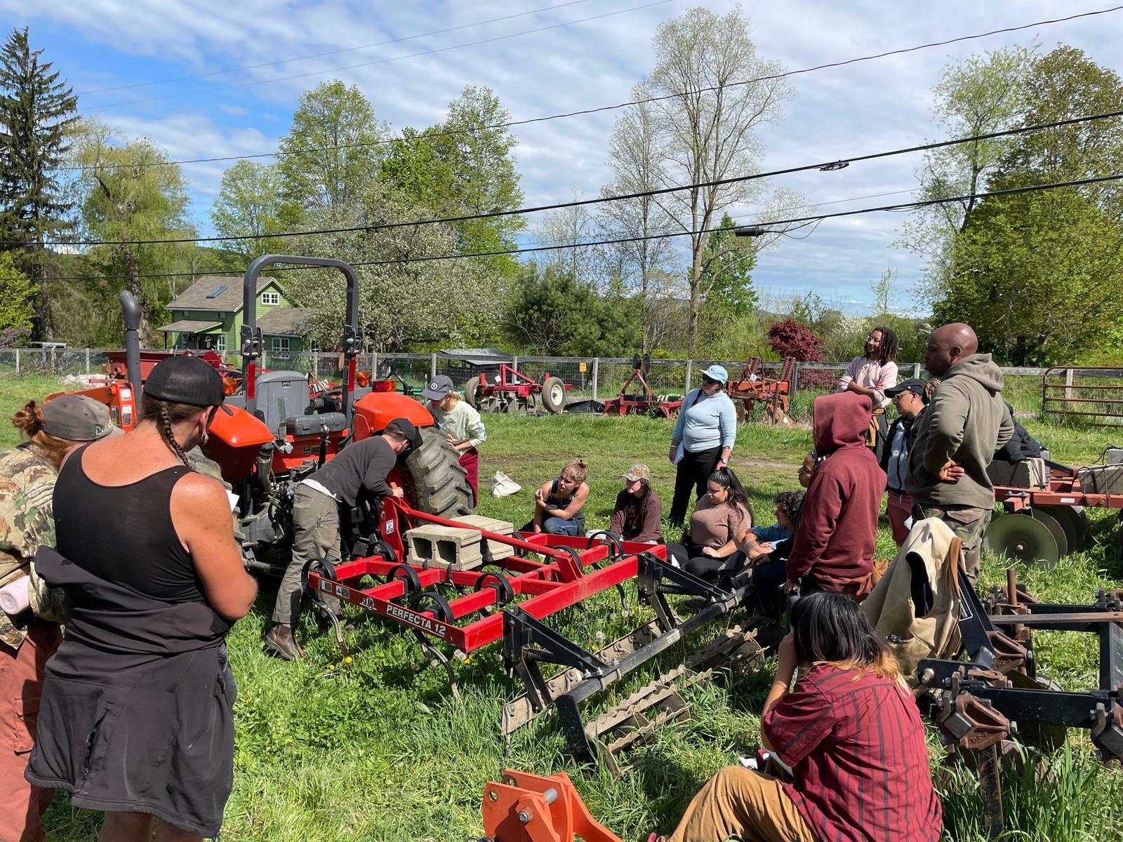 Farmers at Rock Steady Farm gathered around a tractor for a workshop at their farm