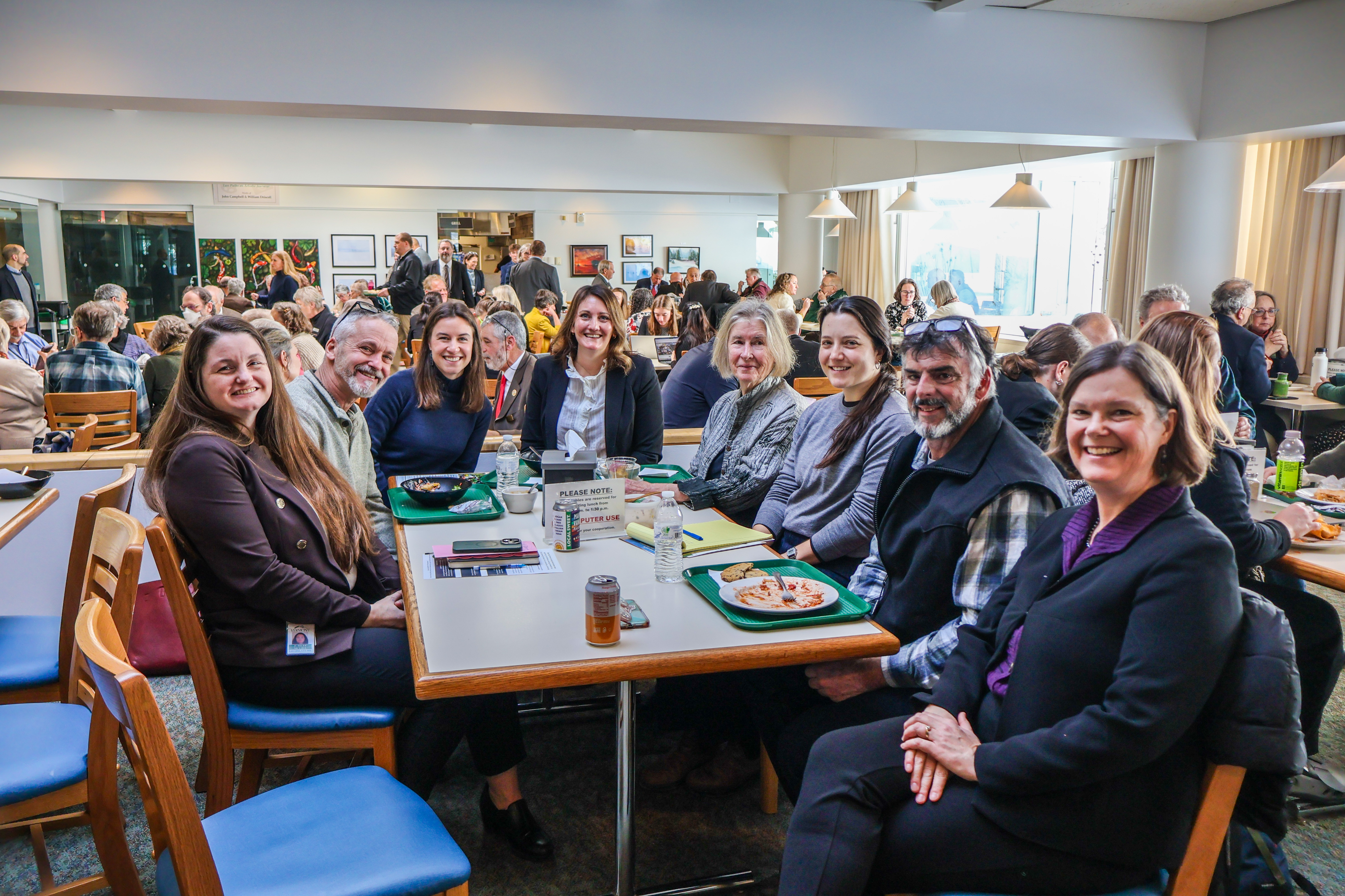 A group of NOFA-VT members and members of the Champlain Valley Farmer Coalition, seated in a table at the State House with Senator Ruth Hardy and Representative Jubilee McGill in the State House cafeteria as part of a recent NOFA-VT State House Day