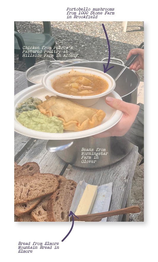 A hand holds a bowl of soup with some veggie and meat sides on the plate next to it.