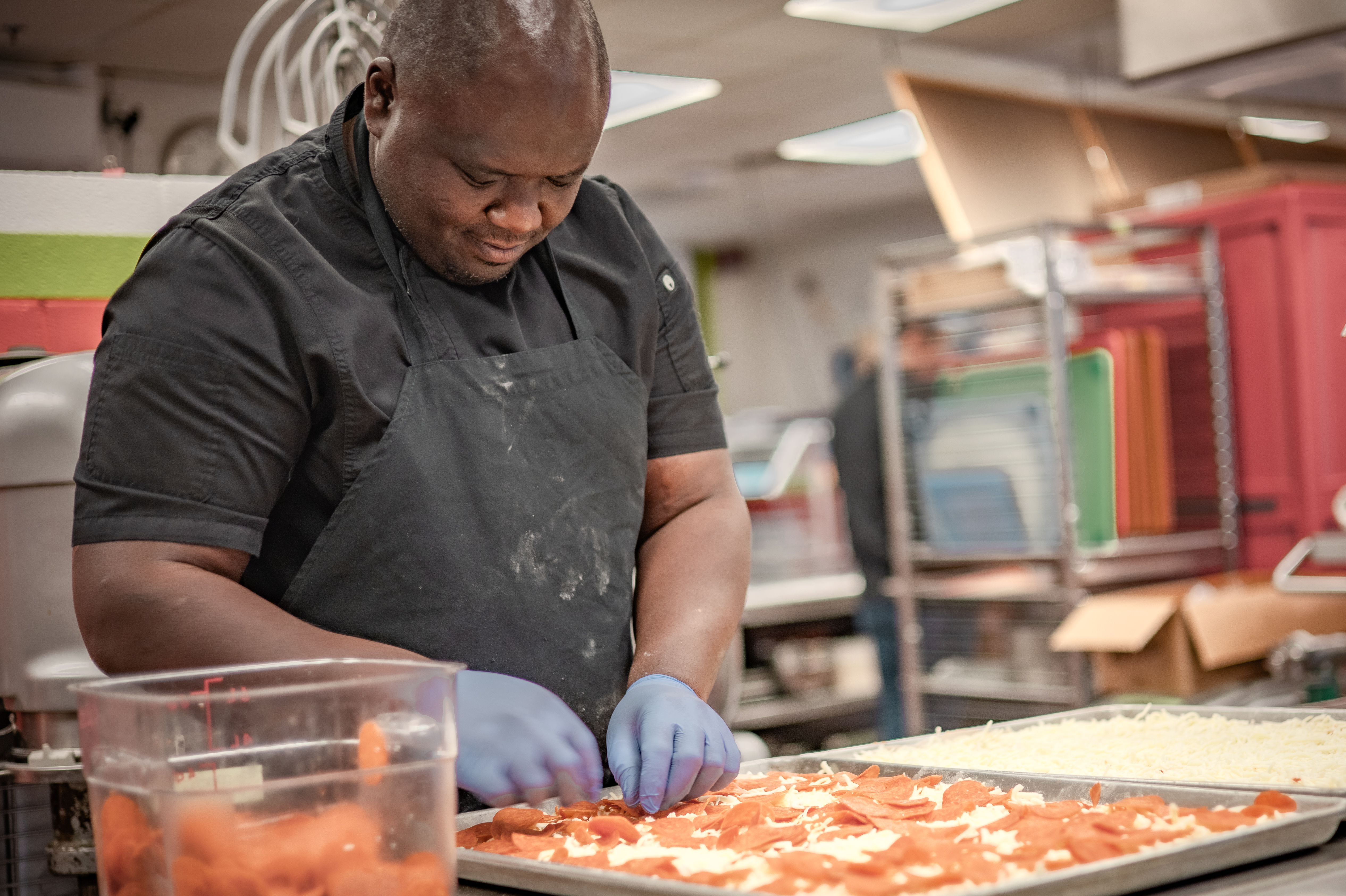 A local food service professional makes a fresh pizza using local ingredients in a school cafeteria