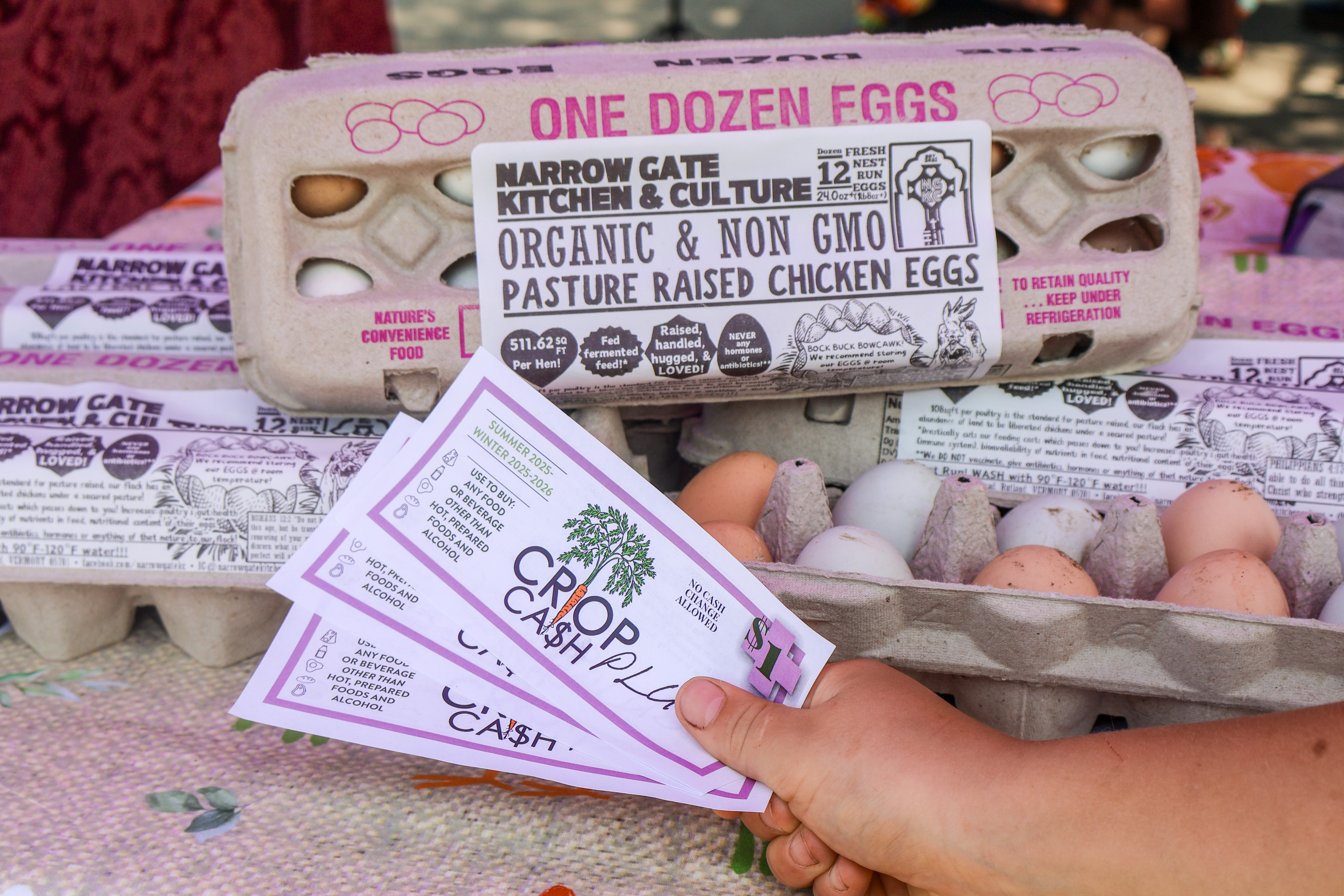 Crop Cash PLUS coupons fanned out in front of an array of eligible products including eggs from Narrow Gate Kitchen & Culture