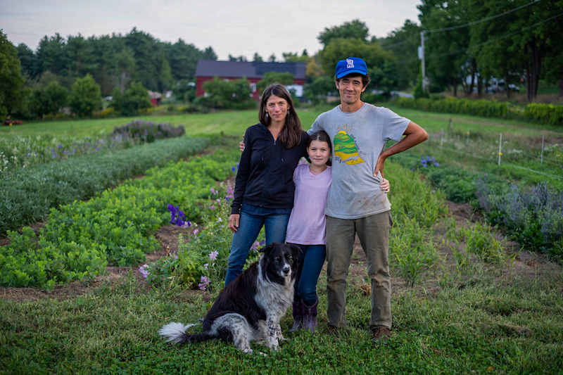 Two adults and a child pose in a farm field