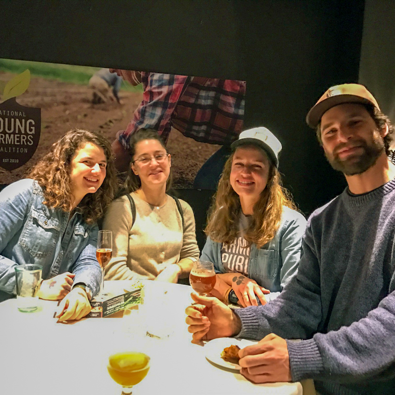 A group of 4 people stand, smiling, at a cocktail table