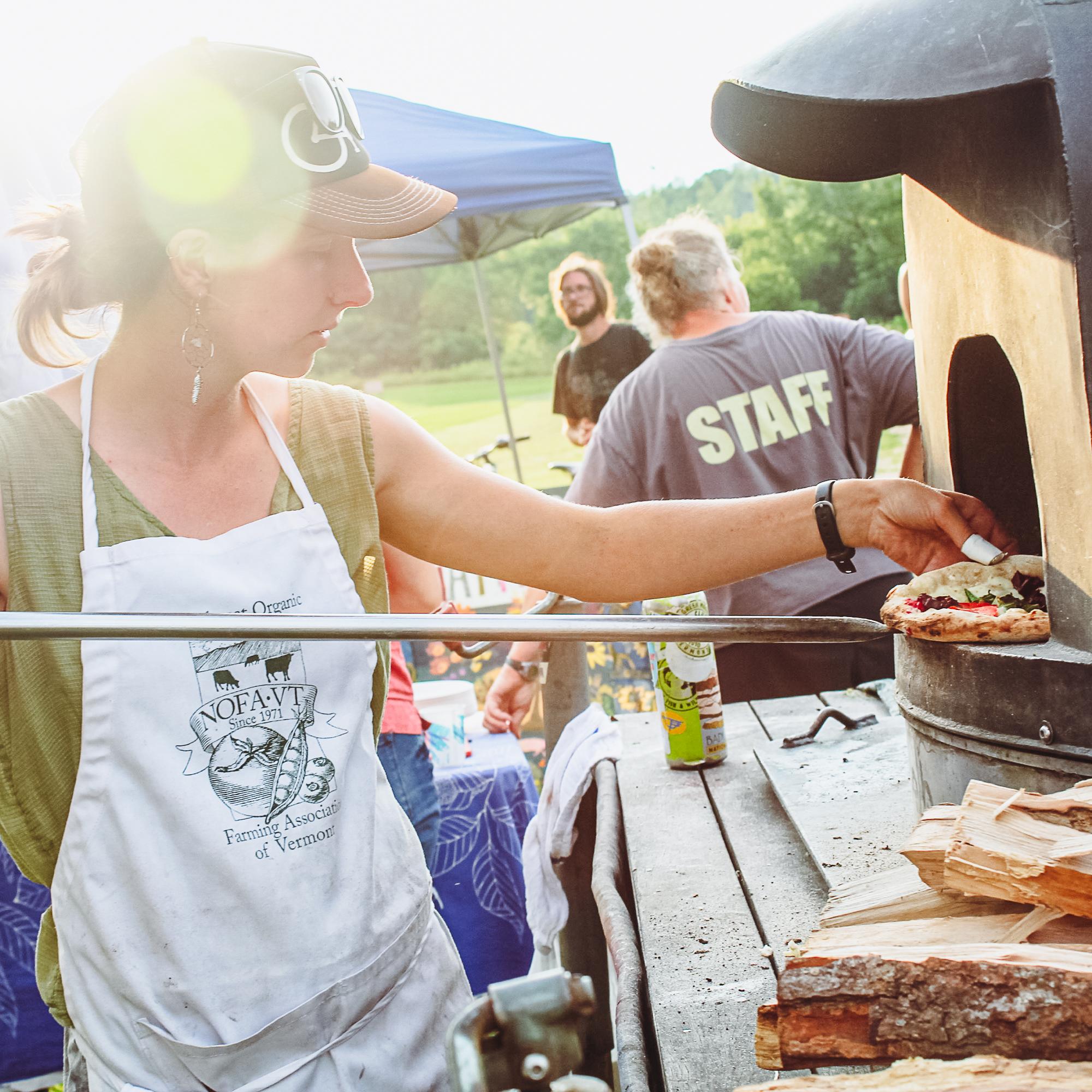 Volunteer cook working the NOFA-VT mobile pizza oven at an on-farm social