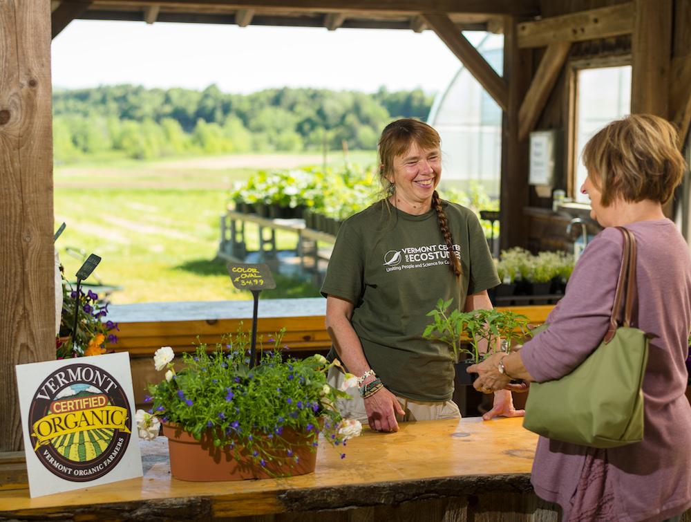 A farmer displays the VOF seal on a farm stand counter.