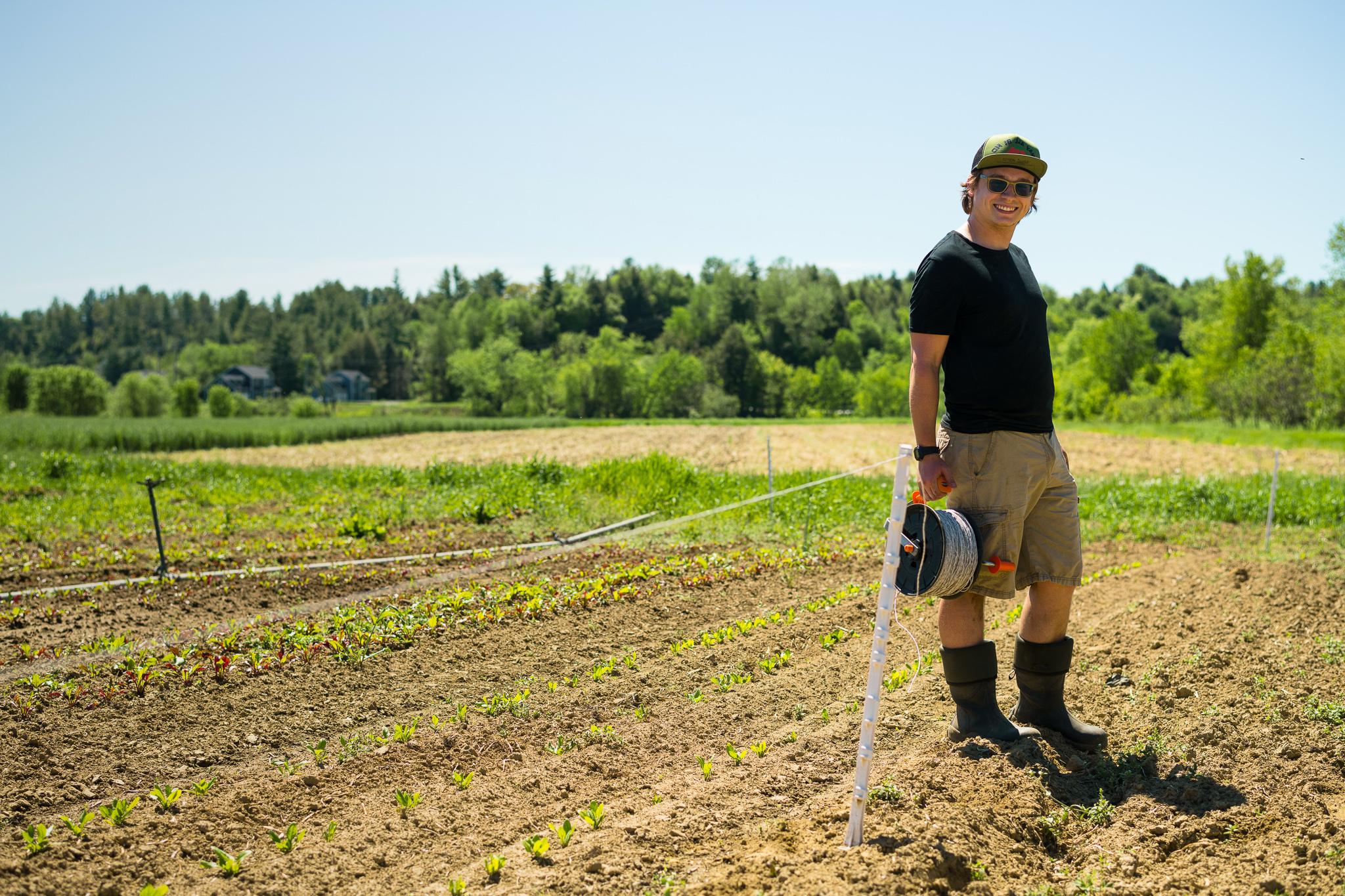 Farmer smiles at the camera while they measure out fencing.