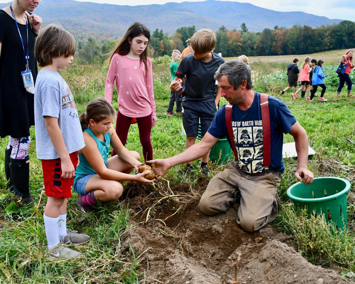 A farmer shows soil to a small group of elementary aged kids