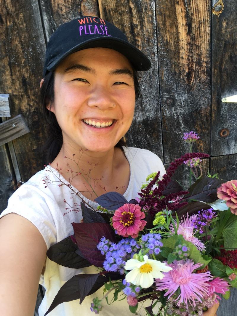 Laura smiles at the camera, holding a bouquet of flowers