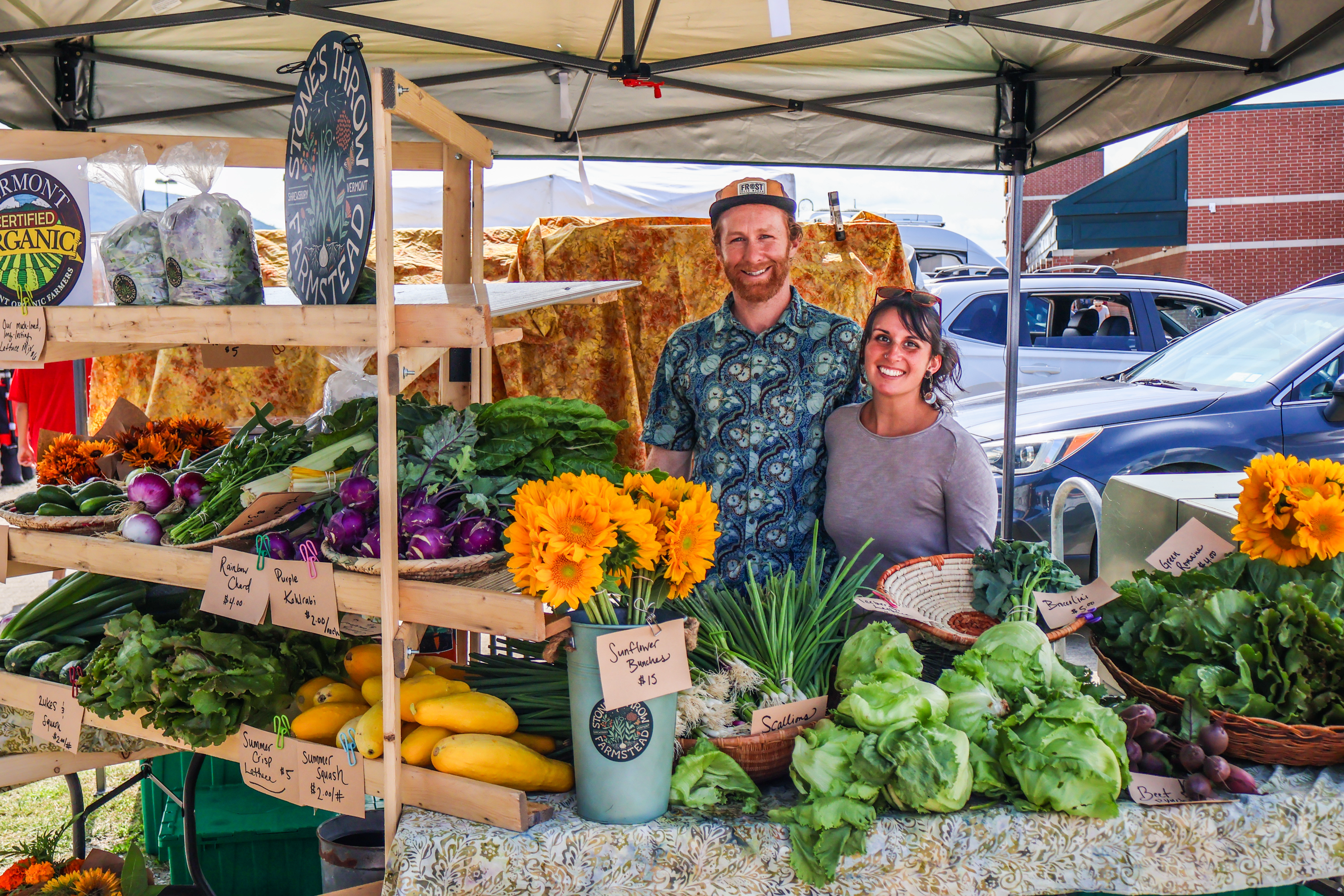 Jess Purks and Connor Self of Stone's Throw Farmstead stand with their colorful array of organic veggies and flowers at the Vermont Farmers Market in Rutland