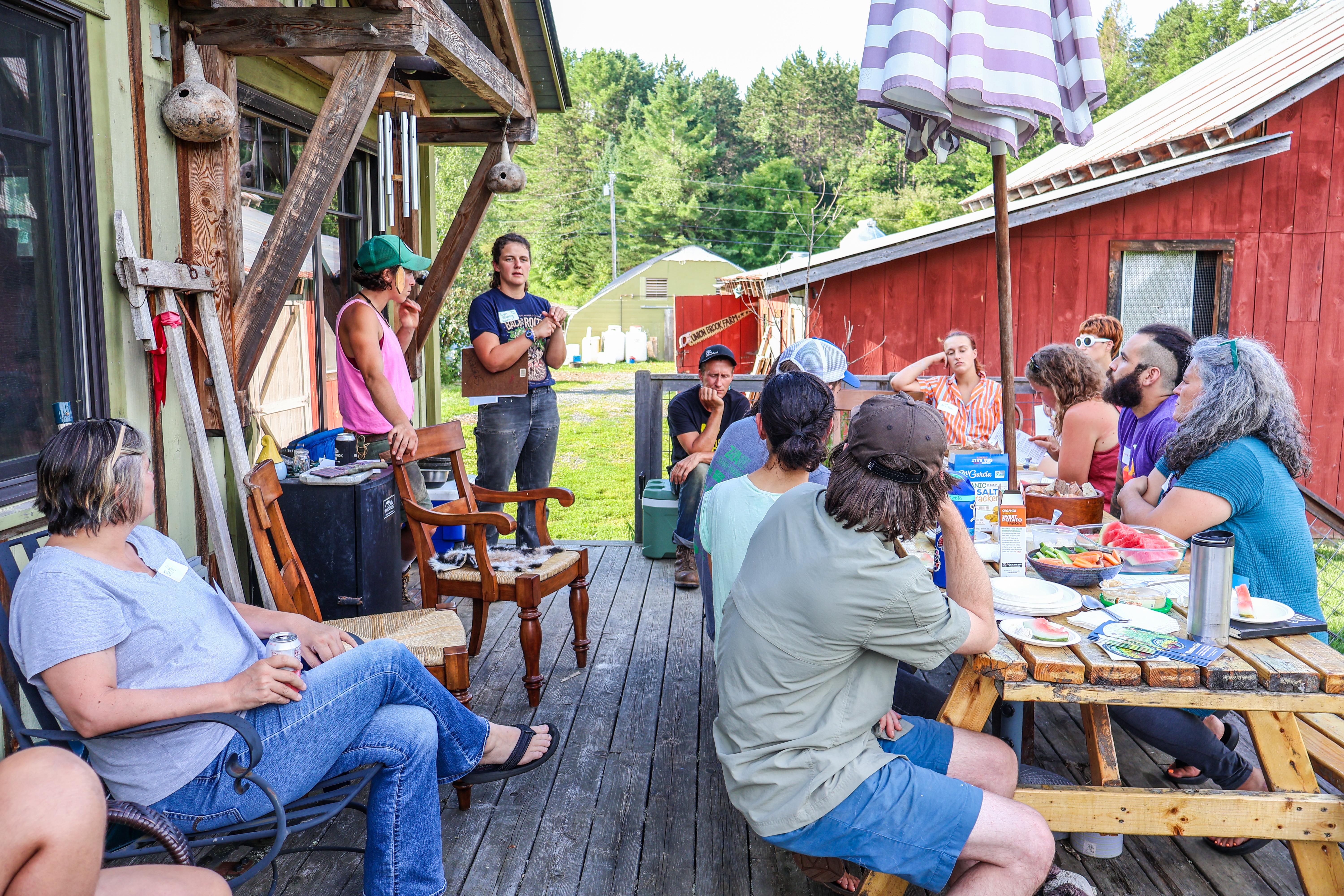 A group of beginning and aspiring farmers gathers on the patio at Union Brook Farm while listing to Megan Browning and Em Virzi share insights into starting a farm