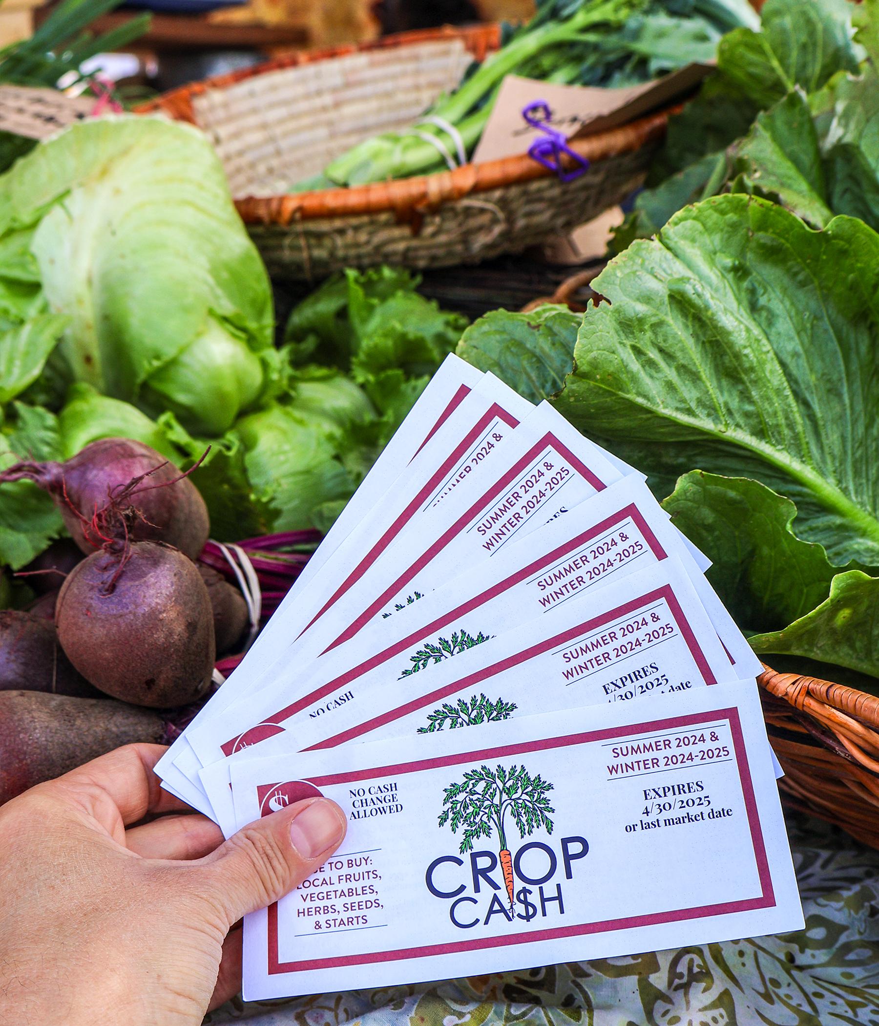 Crop Cash coupons fanned out over colorful produce at a farmers market