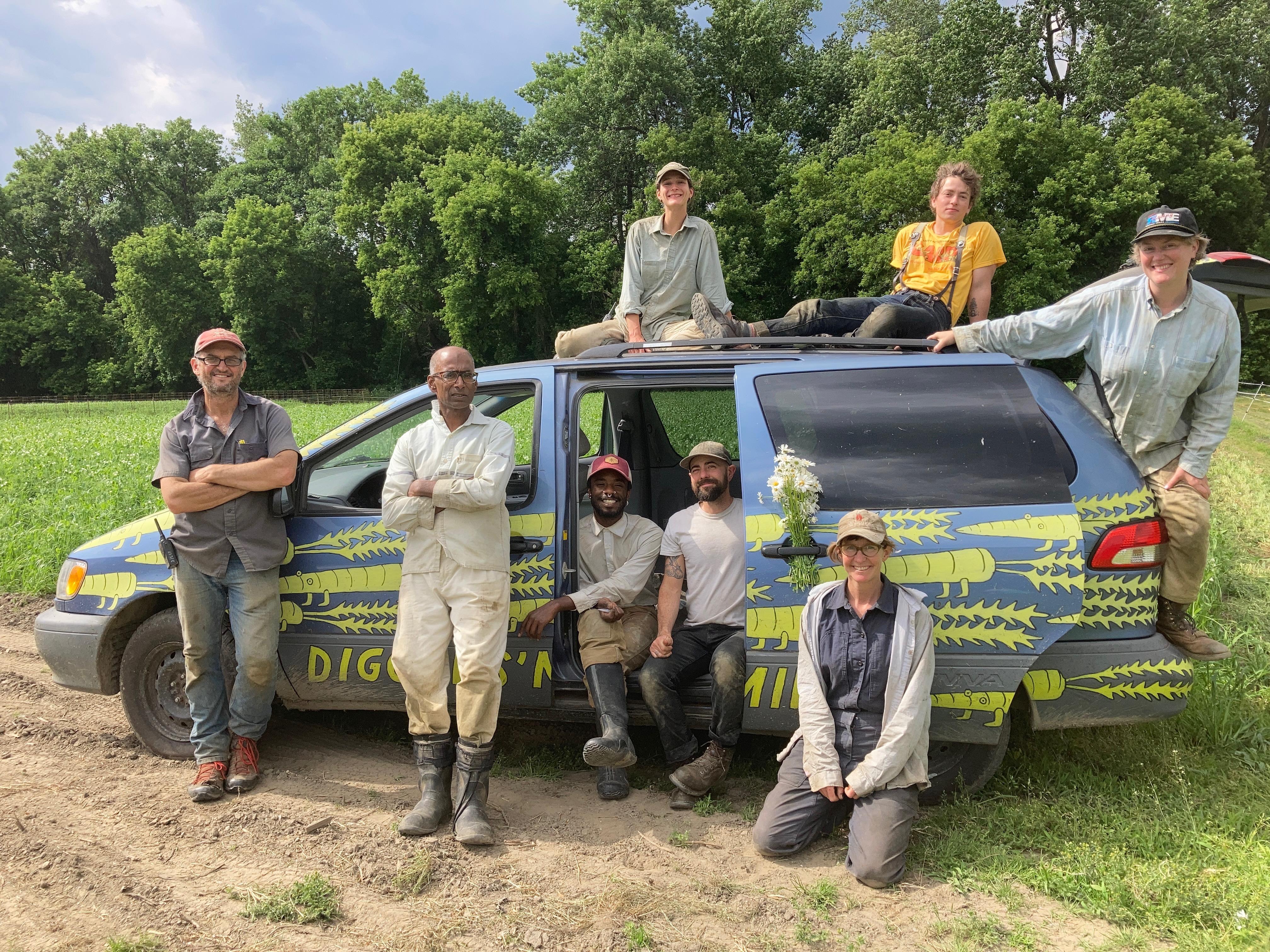 Diggers' Mirth farm crew sitting around and on top of a van painted with animated carrots