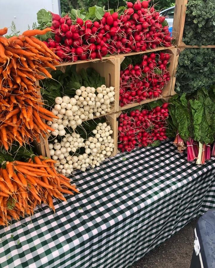 Colorful veggies stacked high on a gingham tablecloth at the farmers market