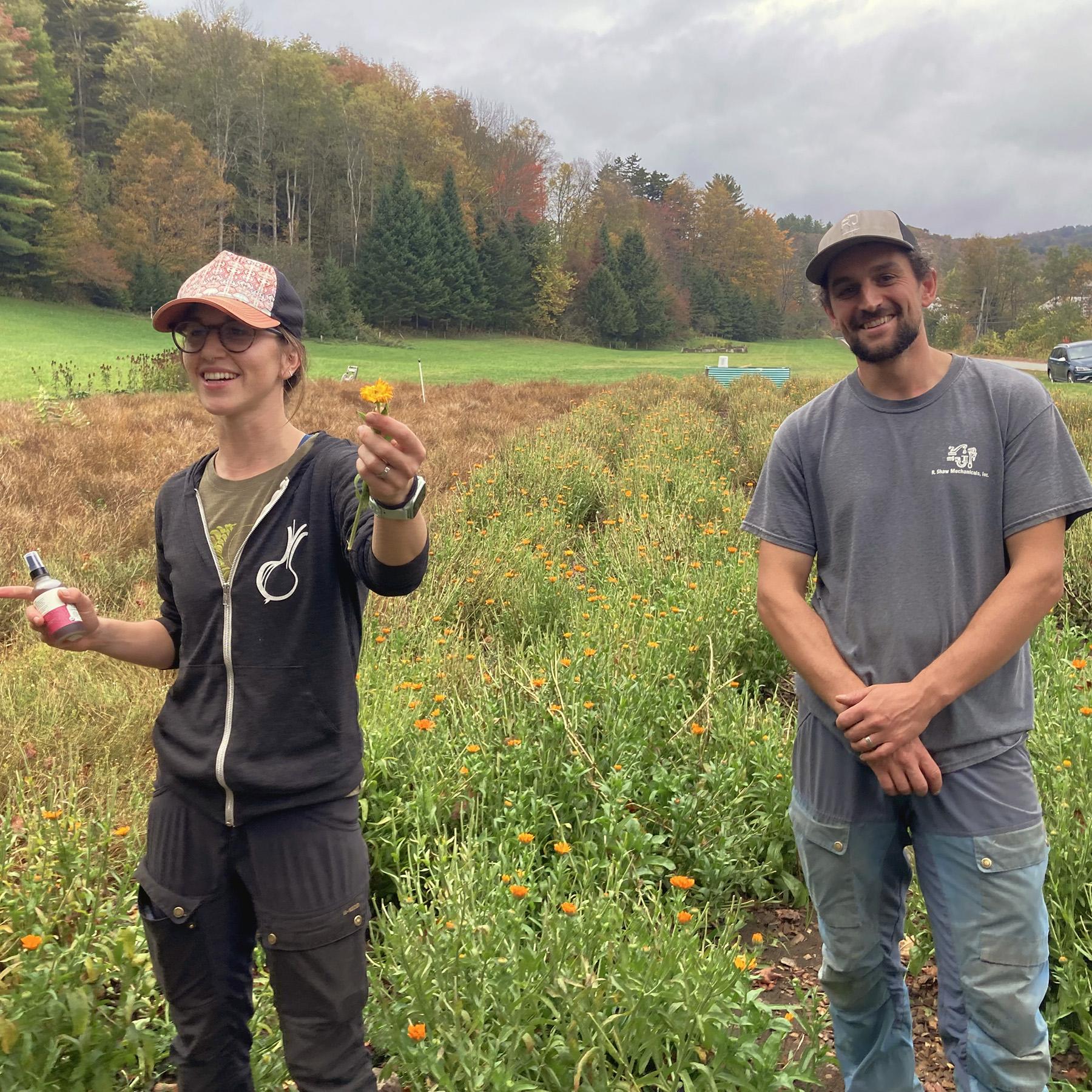 Sarah and Nathan of Hillside Botanicals stand smiling near a row of calendula