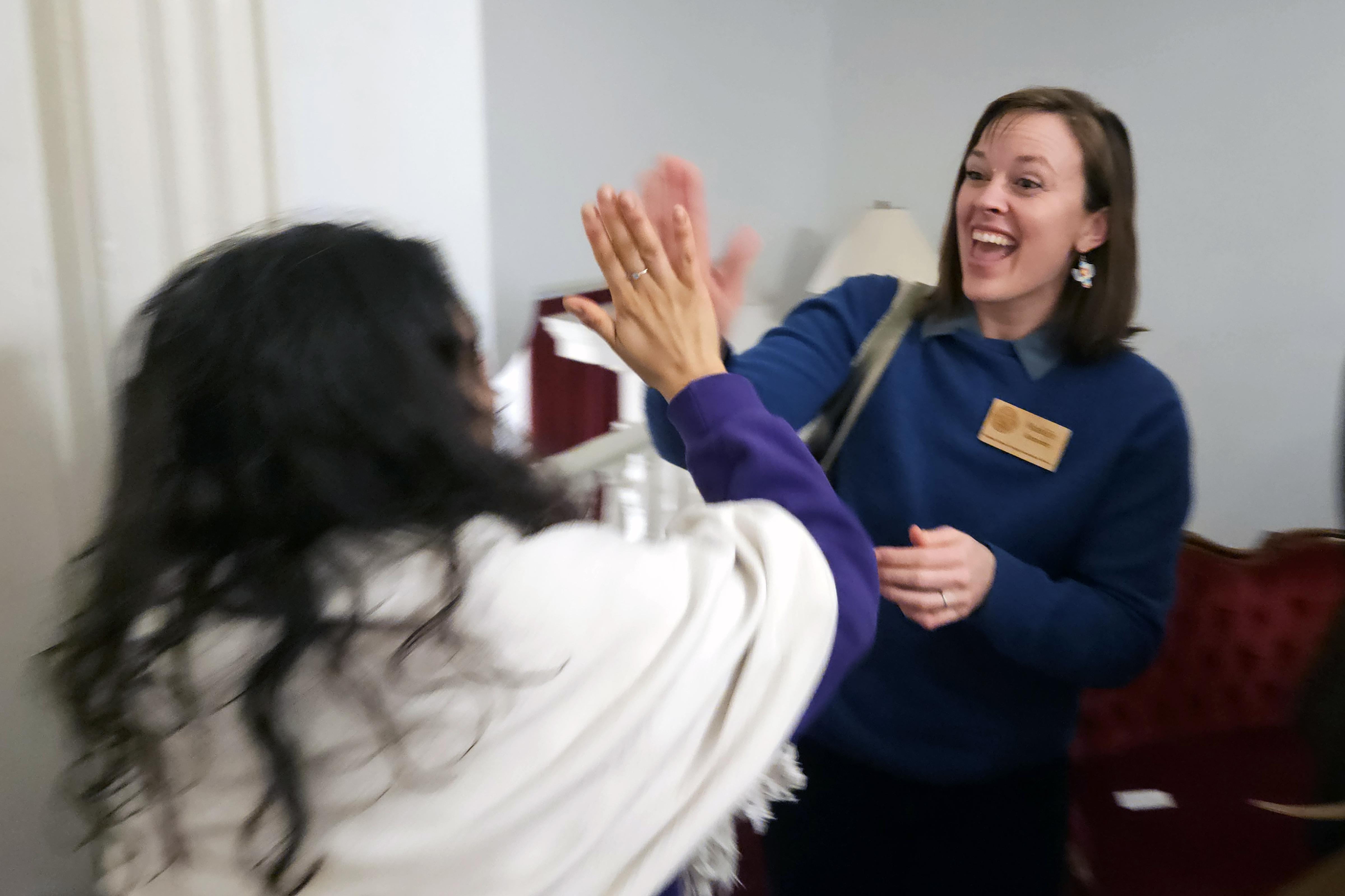 NOFA-VT Policy & Organizing Director Maddie Kempner high-fives NOFA-VT farmer member Melisa Oliva of Ananda Gardens in the hall of the State House upon hearing that S.60 passed the Vermont legislature