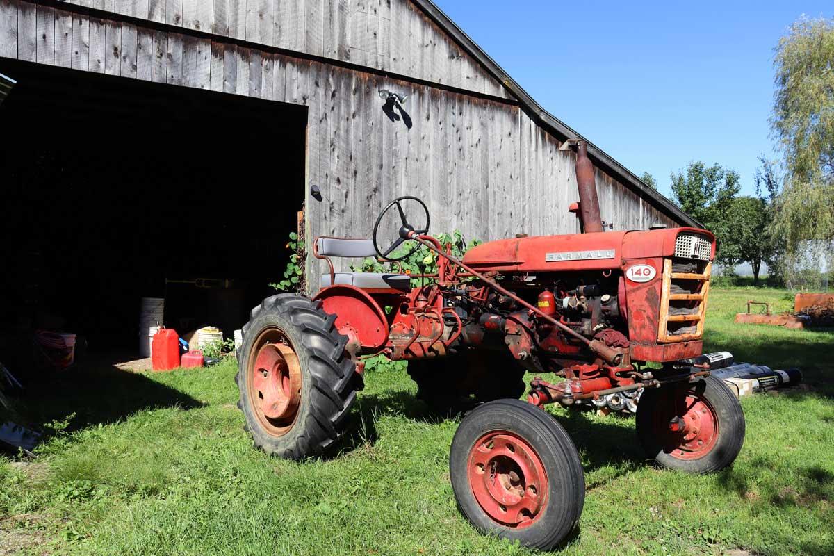 A red Farmall tractor in front of a barn at Old Road Farm 