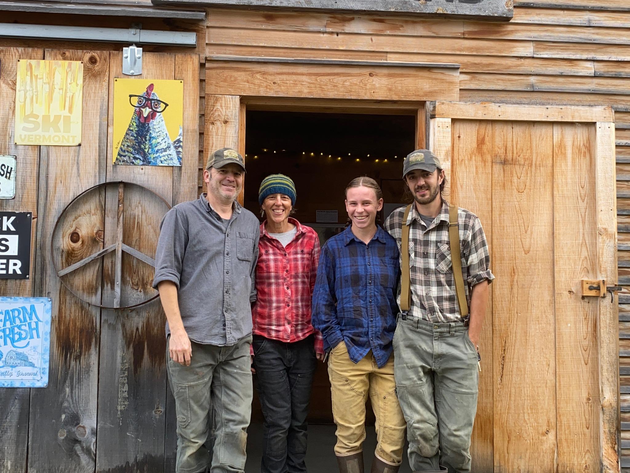 The farmers from Firefly Farm standing arm-in-arm and smiling in front of their barn