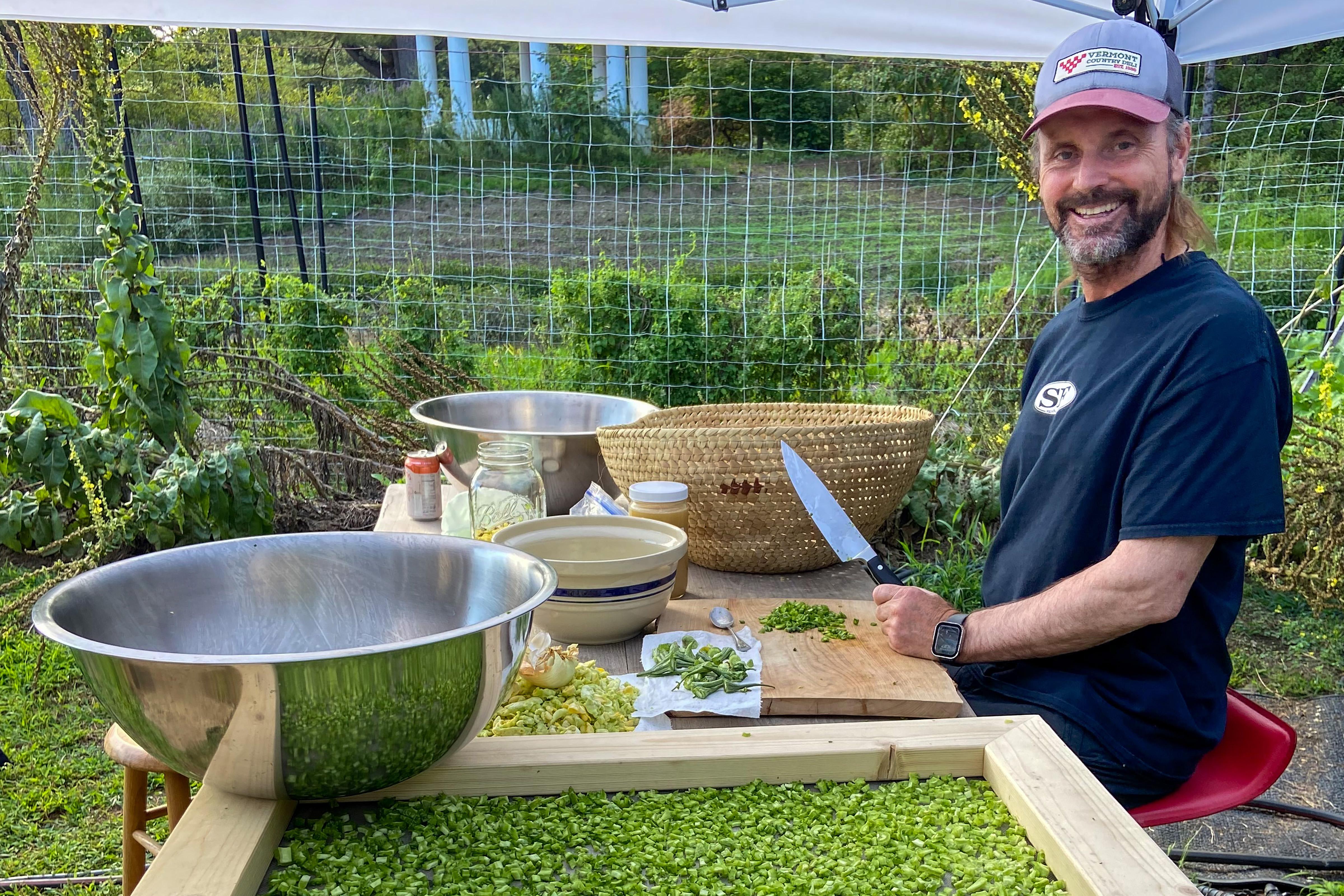 Jay Malouf of Chantry Farm is seen smiling while processing medicinal herbs and laying them on a screen to dry