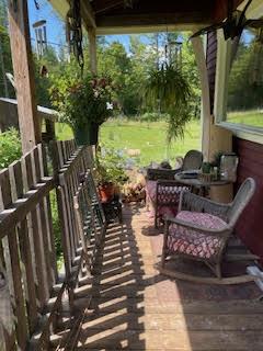 Picture of a wooden porch with wicker chairs, hanging plants, and wind chimes.