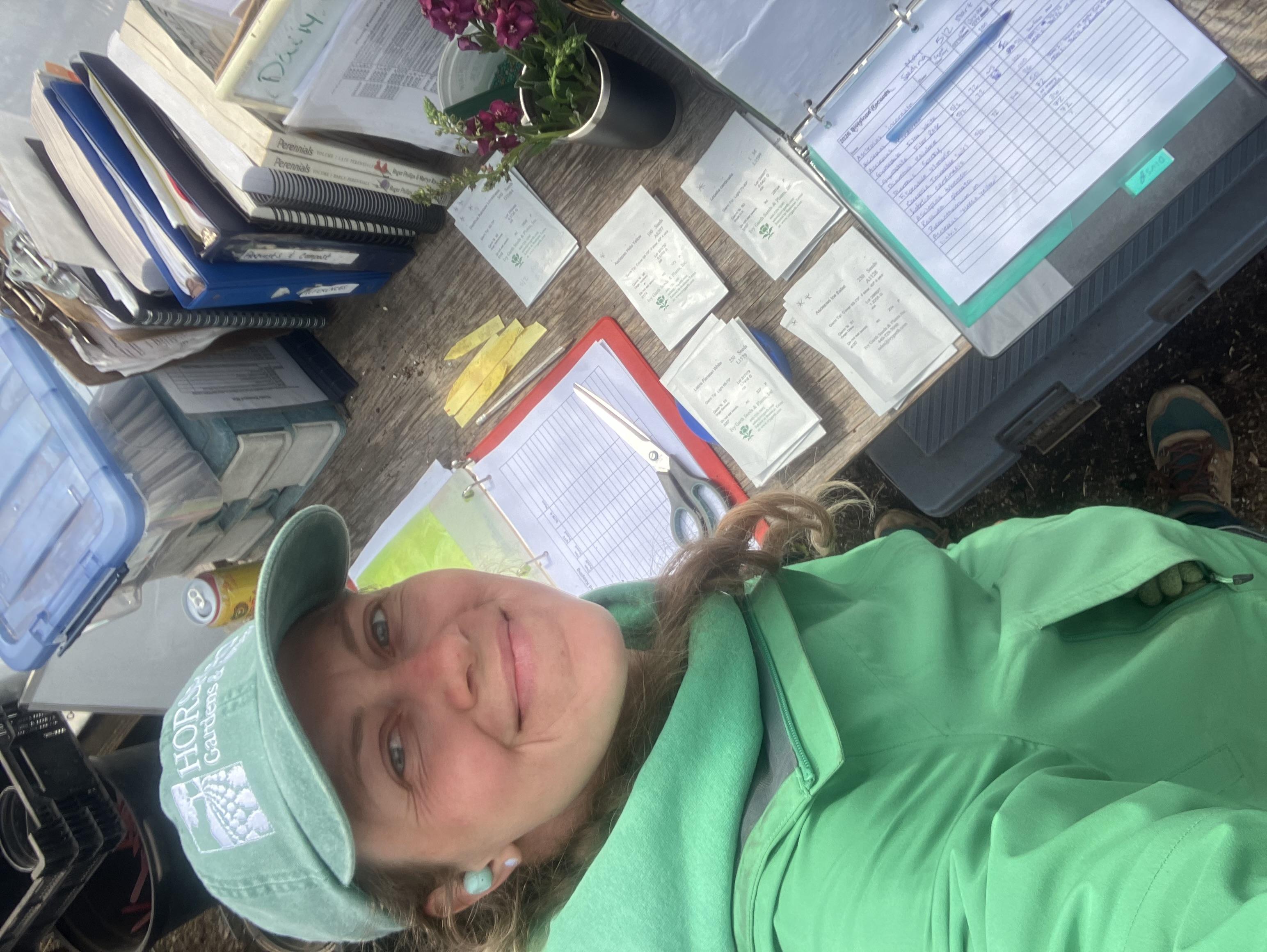 Smiling woman in green hat and jacket with seed packets
