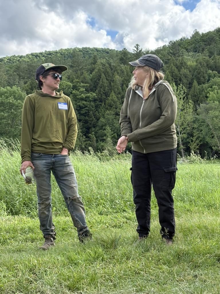 Stoni Tomson of New Tradition Farm and Sarah Jane Williamson of Jubilee Farm stand in a field chatting with Land Together Learning Network participants about their experiences sharing land in Huntington