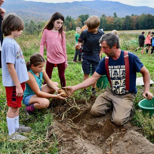 A farmer shows soil to a small group of elementary aged kids