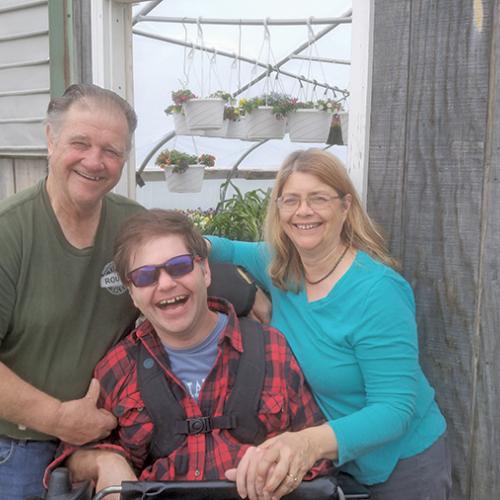 Family at Valley Dream Farm standing in front of a greenhouse, smiling