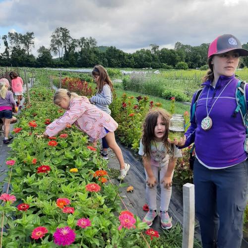 children and camp counselor in flower garden