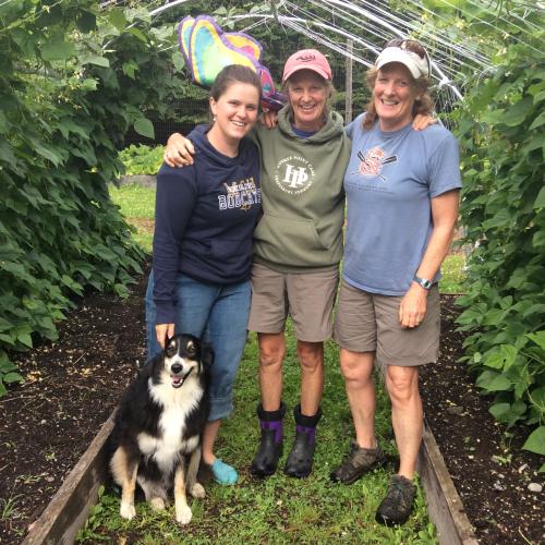 three people and a dog surrounded by bean vines