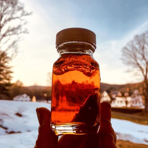 Holding maple syrup in front of a farm scene