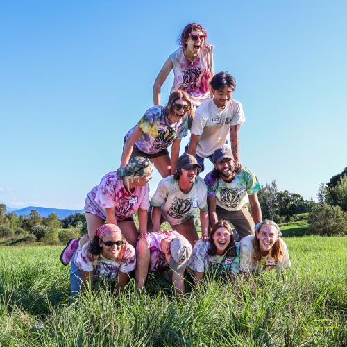 Farmers and farmworkers wearing huge grins and matching tie-dye tees as they make a human pyramid at the 2024 Farmer Olympics 