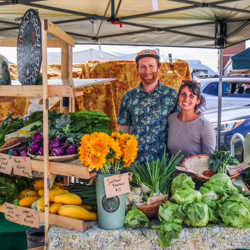 Jess Purks and Connor Self of Stone's Throw Farmstead stand with their colorful array of organic veggies and flowers at the Vermont Farmers Market in Rutland