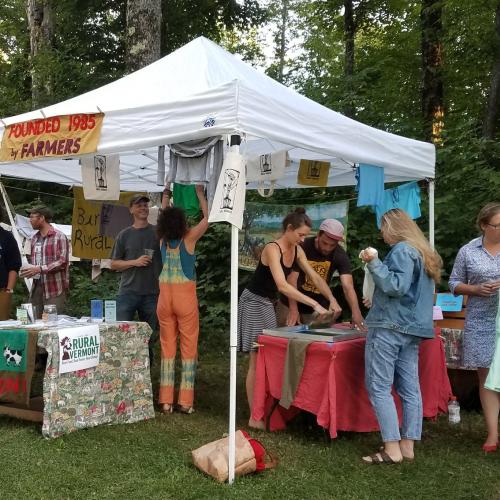 group of people screen printing tees under a tent