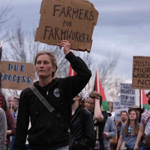 NOFA-VT member and farmer Mollie Griffin of Glinnis Hill Farm carrying a sign reading "Farmers for Farmworkers" as part of a community solidarity march