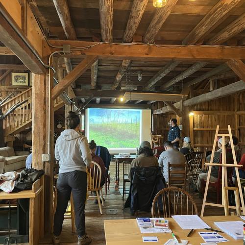 People standing in a barn watching a powerpoint presentation