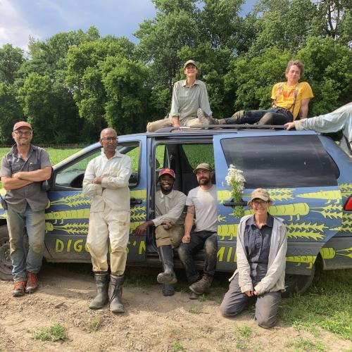 Diggers' Mirth farm crew sitting around and on top of a van painted with animated carrots