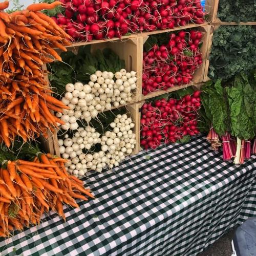 Colorful veggies stacked high on a gingham tablecloth at the farmers market