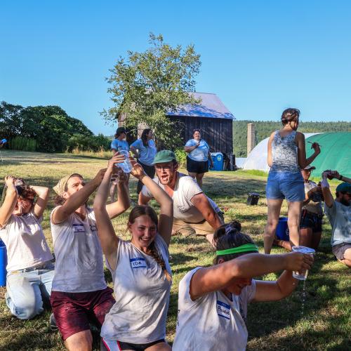 Farmers participate in a water pouring relay as part of the 2025 Farmer Olympics at High Meadows Farm
