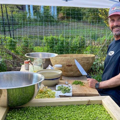 Jay Malouf of Chantry Farm is seen smiling while processing medicinal herbs and laying them on a screen to dry