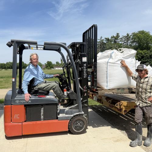 Todd Hardie of the Champlain Valley Grain Center is seen seated on a forklift receiving a load of fresh grain from Tyler of Granite Grains