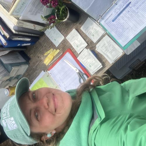 Smiling woman in green hat and jacket with seed packets